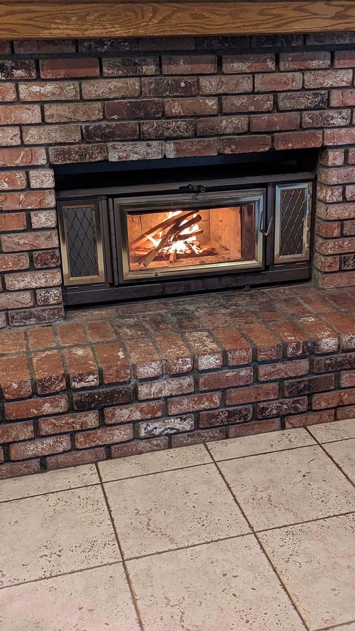 Brick fireplace with an insert and an active fire